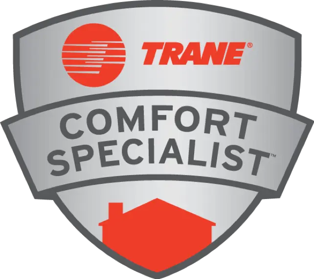 A silver and gray badge with the red Trane logo and text TRANE Comfort Specialist. A red house icon is at the bottom of the badge.